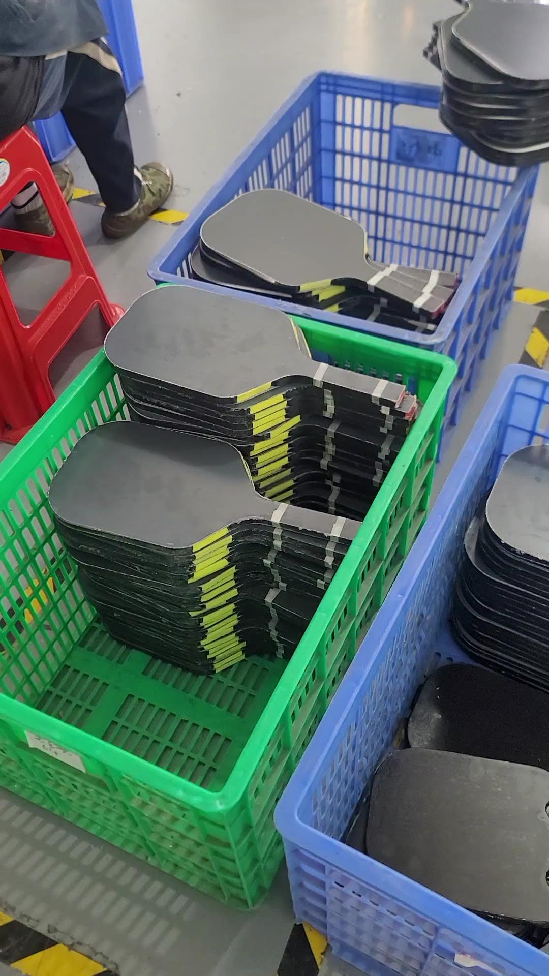 Batches of unfinished pickleball paddles sorted in factory baskets