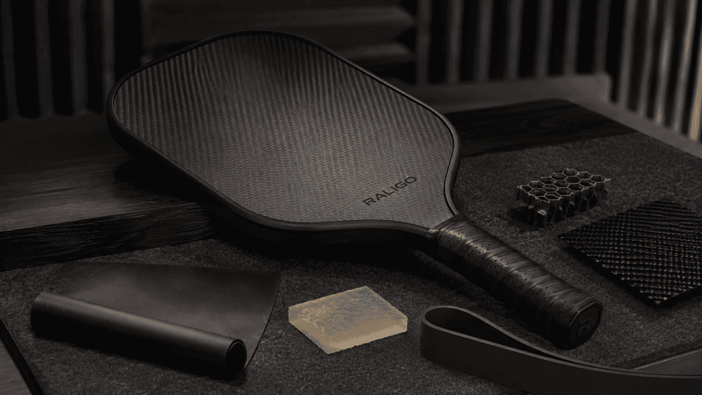Carbon fiber pickleball paddle with quiet damping materials presented in a premium commercial still-life setting