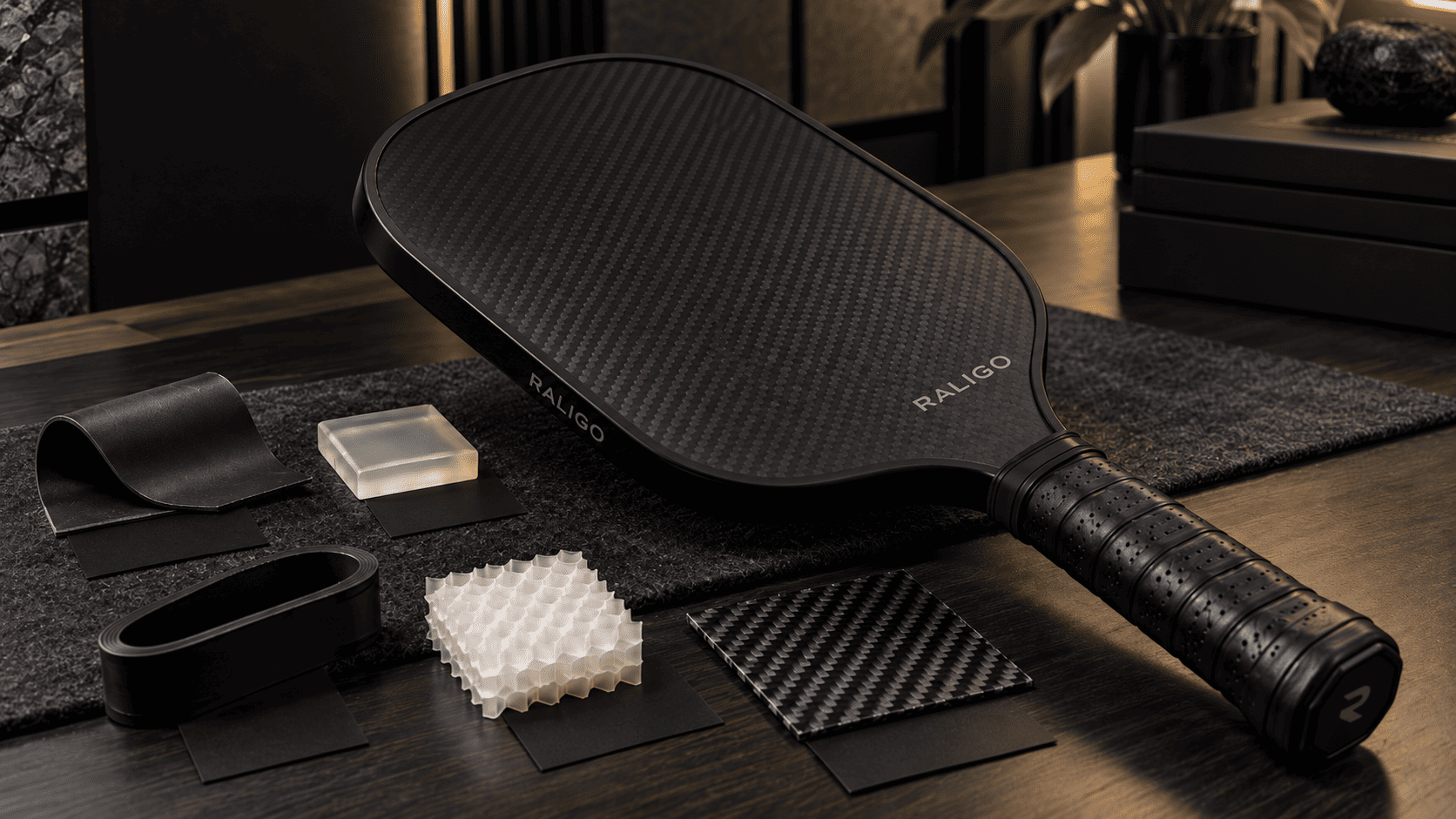 Carbon fiber pickleball paddle with rubber film, elastomer gel, urethane strip, and honeycomb core samples for vibration damping engineering